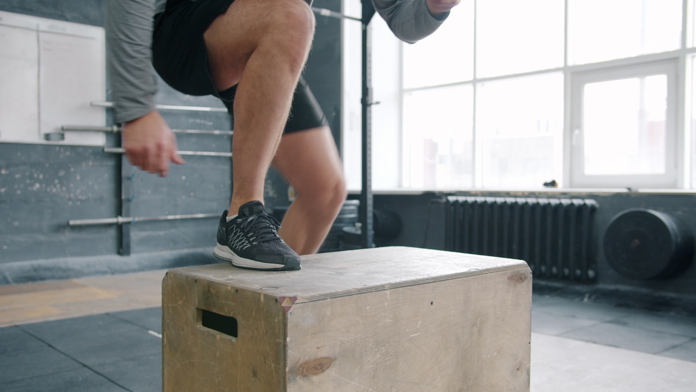 Athlete landing a box jump in a gym — rebuilding landing mechanics and single-leg control during ankle sprain return-to-sport rehab in Tampa.