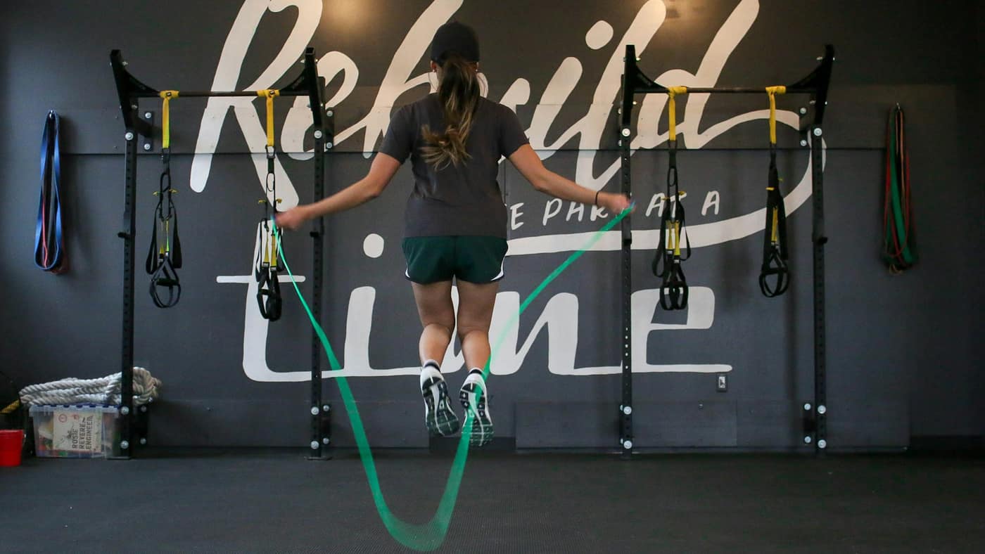 Athlete jumping rope in a gym — the low, springy hopping that comes back late in calf strain rehab, before running fast again.
