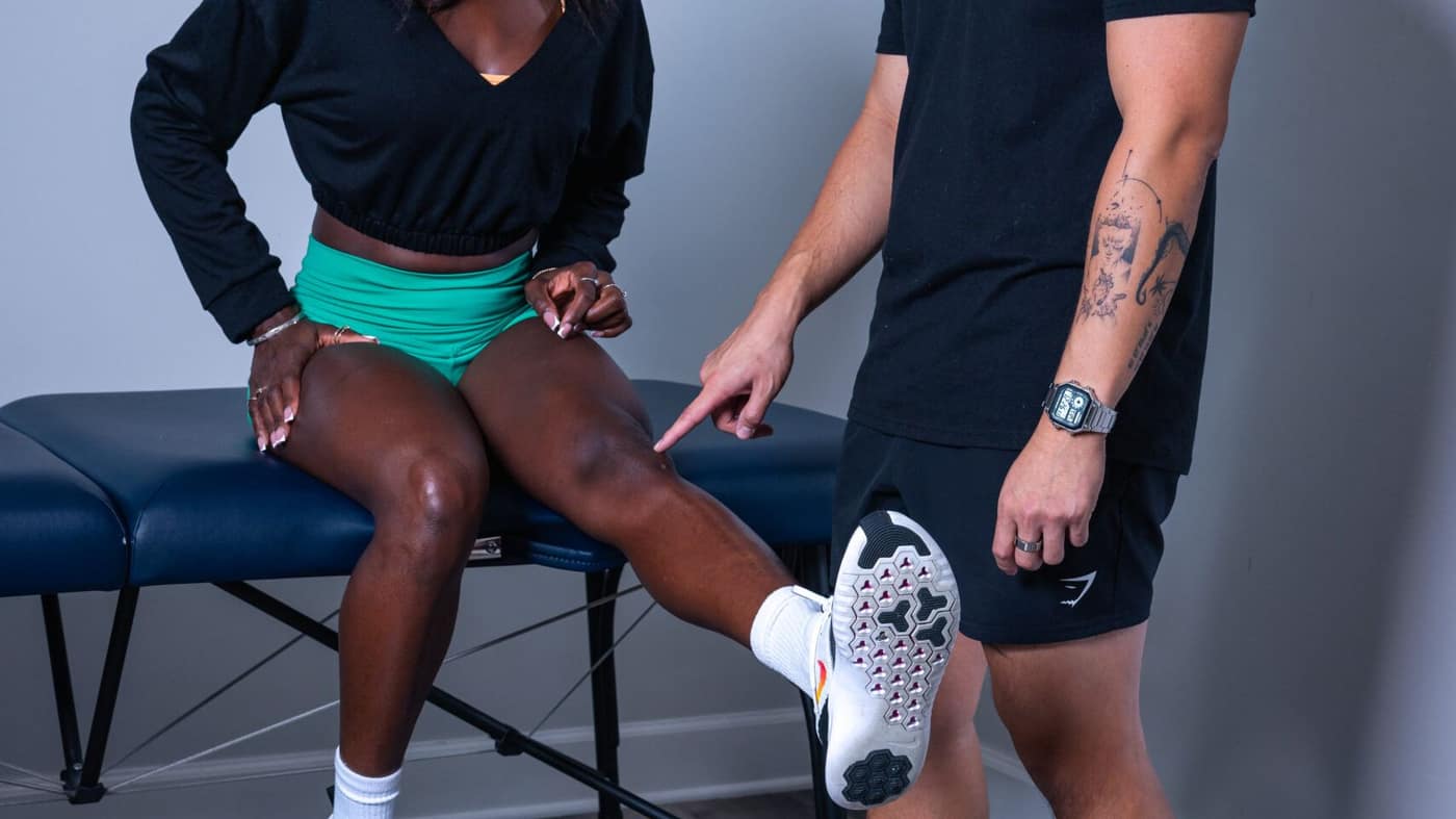 Forward Physio doctor of physical therapy pointing to the joint line of a seated athlete’s knee during an exam — part of a meniscus tear physical therapy evaluation in Tampa.