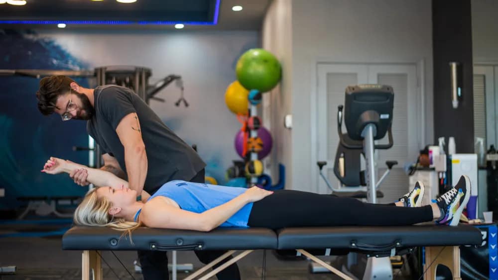 Forward Physio doctor of physical therapy assessing an athlete’s overhead shoulder range of motion on a treatment table — part of a shoulder pain physical therapy evaluation in Tampa.