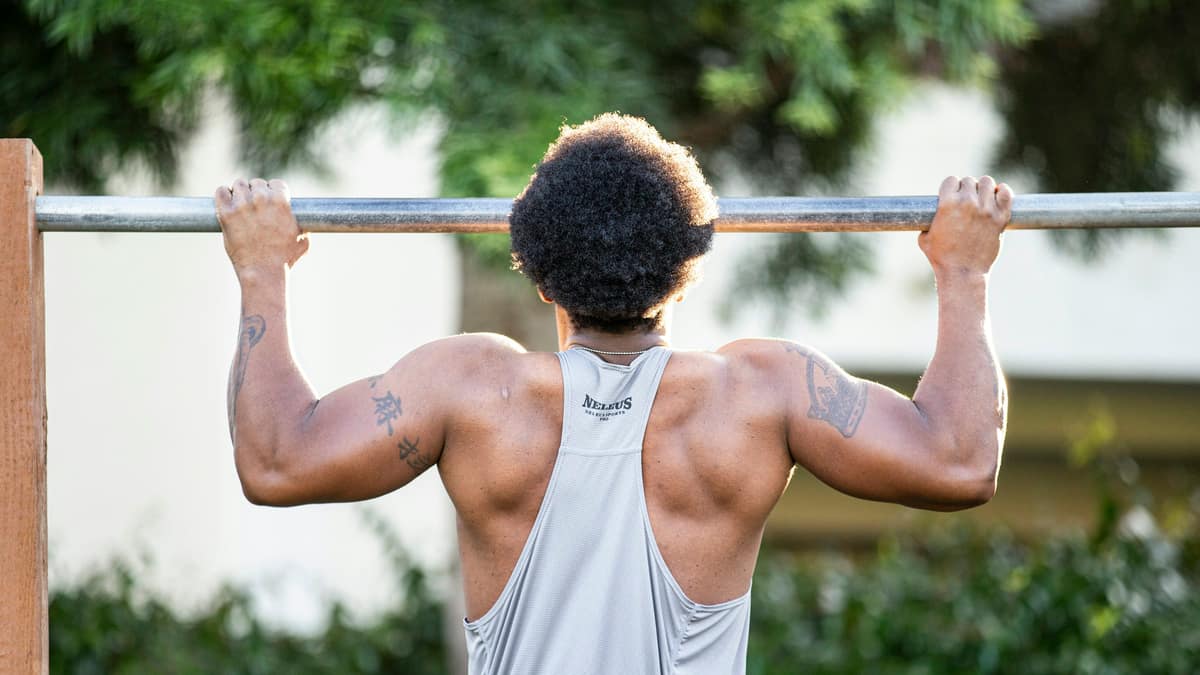 Athlete mid pull-up on an outdoor bar, forearms and elbows working hard &mdash; tennis elbow physical therapy for lifters and hybrid athletes at Forward Physio Tampa