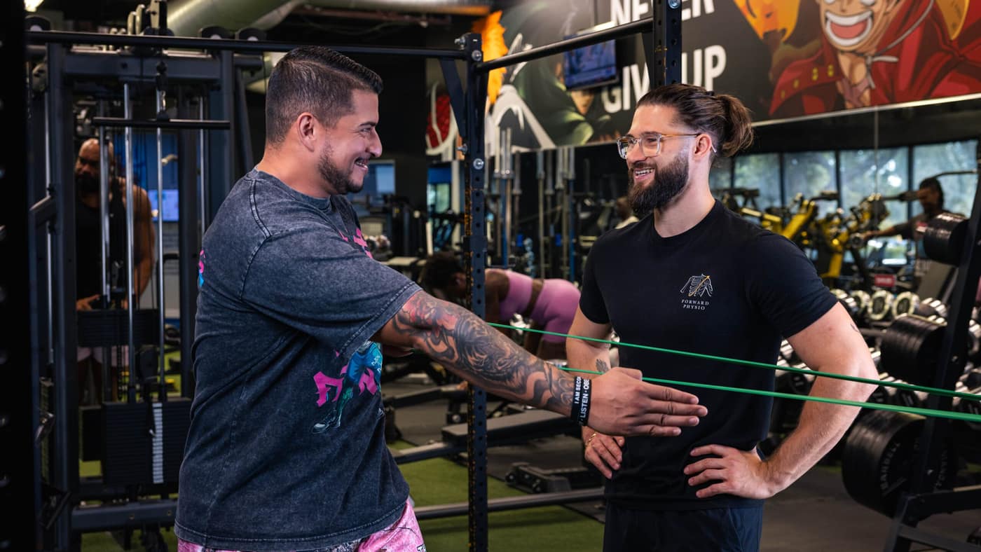 Forward Physio doctor of physical therapy coaching an athlete through banded arm and grip work — the progressive loading at the core of tennis elbow rehab in Tampa.